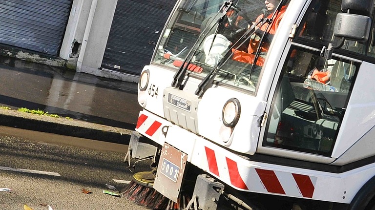 Un camion balais mécanique de Pantin nettoyant une rue de la ville.