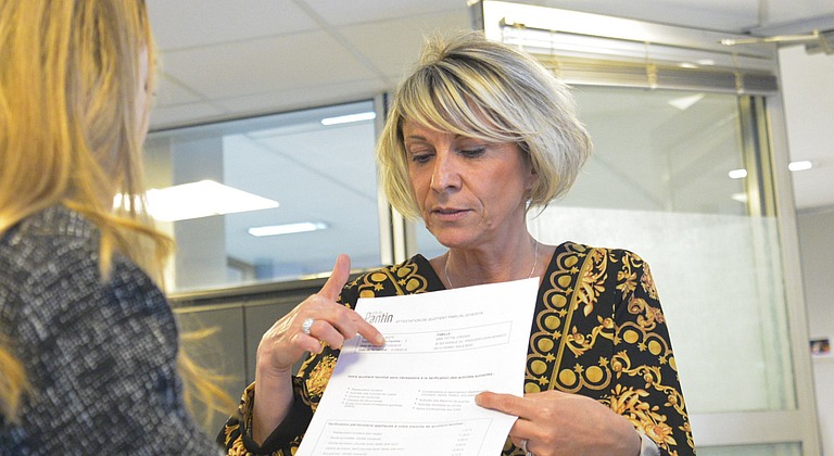Un agent du pôle facturation périscolaire et recouvrement de Pantin montre à une femme son attestation de calcul du quotient familial