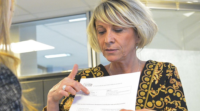 Un agent du pôle facturation périscolaire et recouvrement de Pantin montre à une femme son attestation de calcul du quotient familial