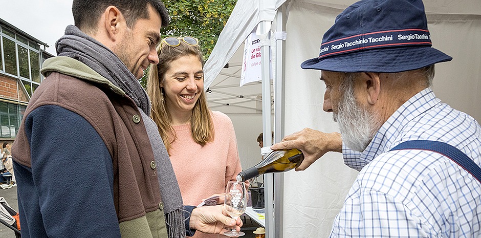 Pohoto représentant un jeune couple se faisant servir un verre de vin par un vigneron pendant le salon Pantin boit bio